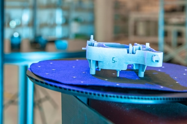 1669510195-cropped 3D printed piece with the number 5 written on it on the the 3D printing platform